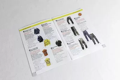 Three unfolded product guide pages with yellow header bands displaying clothing items and descriptions, laid flat on a white surface, showing various apparel options with text and product photography.