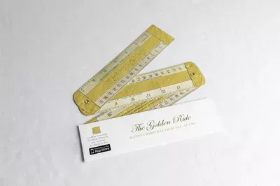 Two golden rulers arranged in an open position next to a white card labeled 