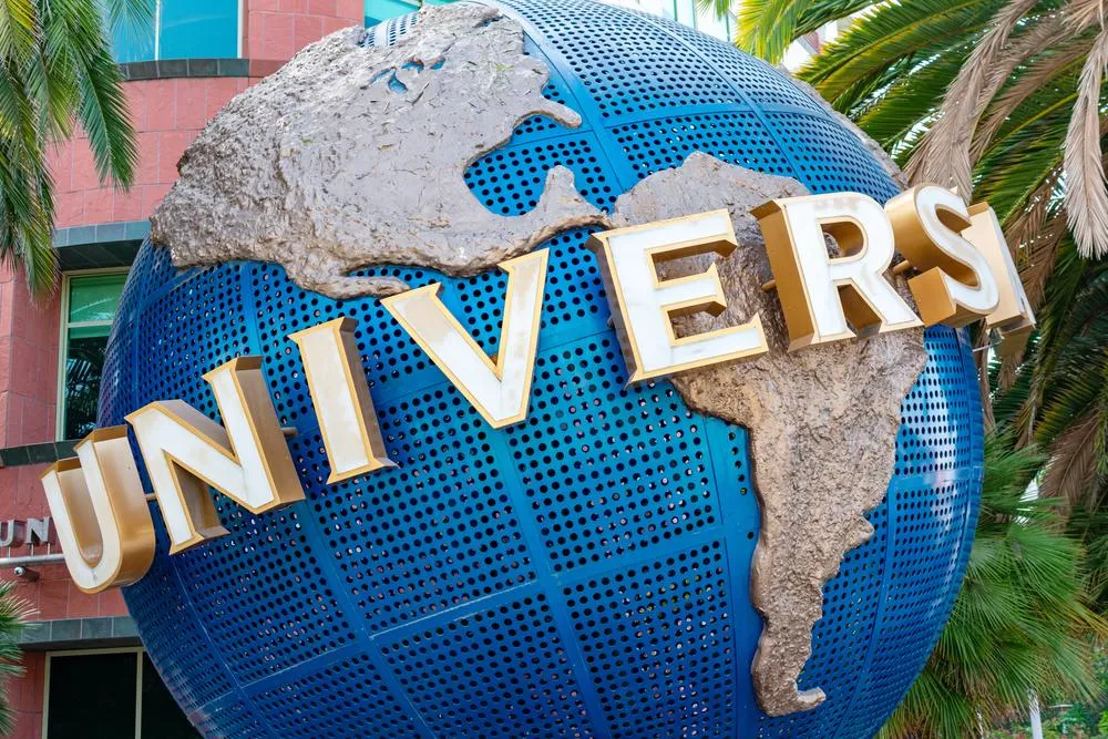 A large blue globe with white grid lines and continents, with a rough stone or rock texture overlaid on top, and gold letters spelling 