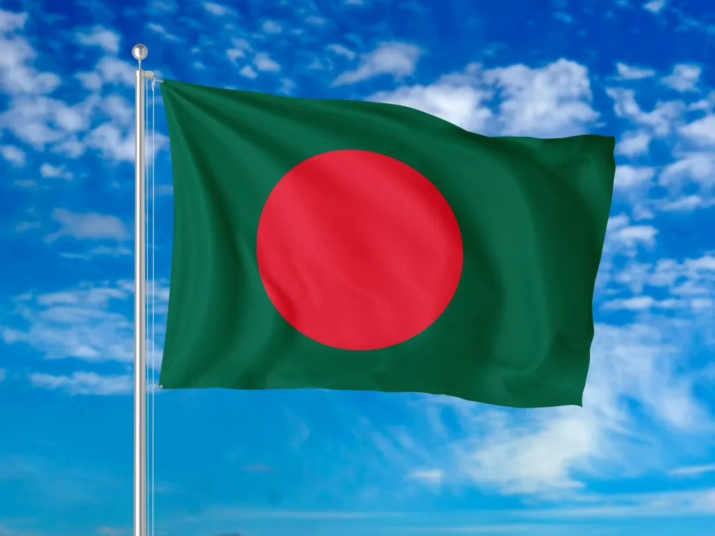 Flag of Bangladesh flying against a blue sky.