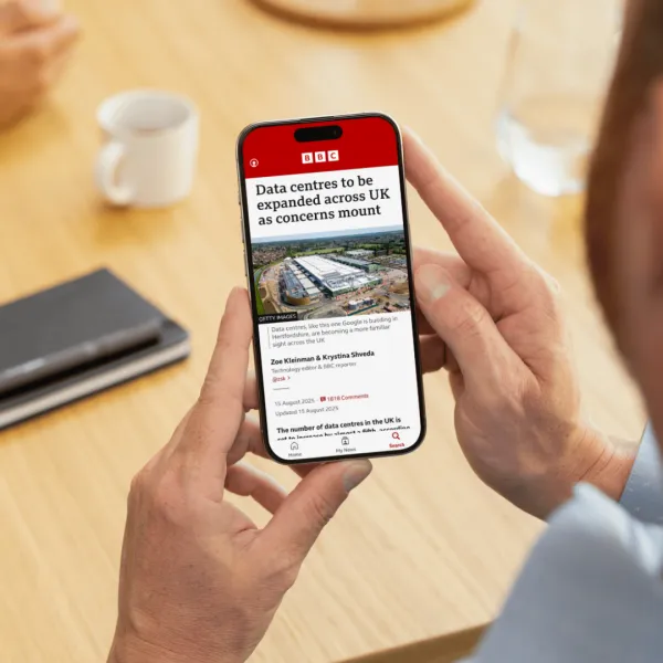A person's hands holding a smartphone displaying a BBC News article titled 