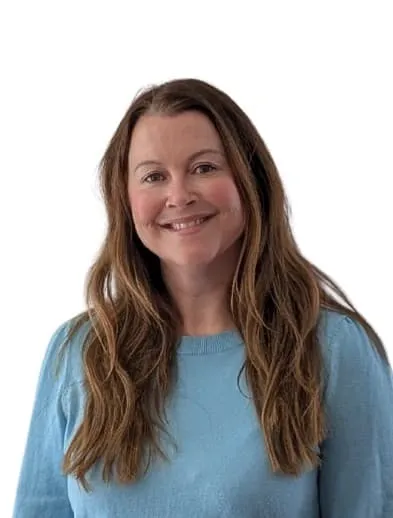 A smiling woman with long brown hair with highlights wearing a light blue sweater against a white background.