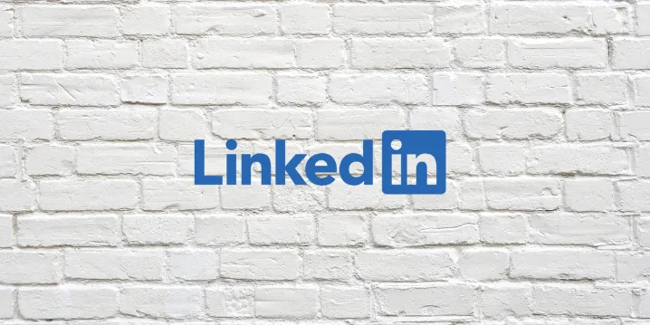 LinkedIn logo in blue text on a white brick wall background.