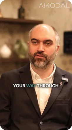 A professional man with a beard wearing a dark blazer and white dress shirt stands in an indoor setting. The text "YOUR WAY THROUGH" appears at the bottom of the image with the Amodal logo visible at the top.